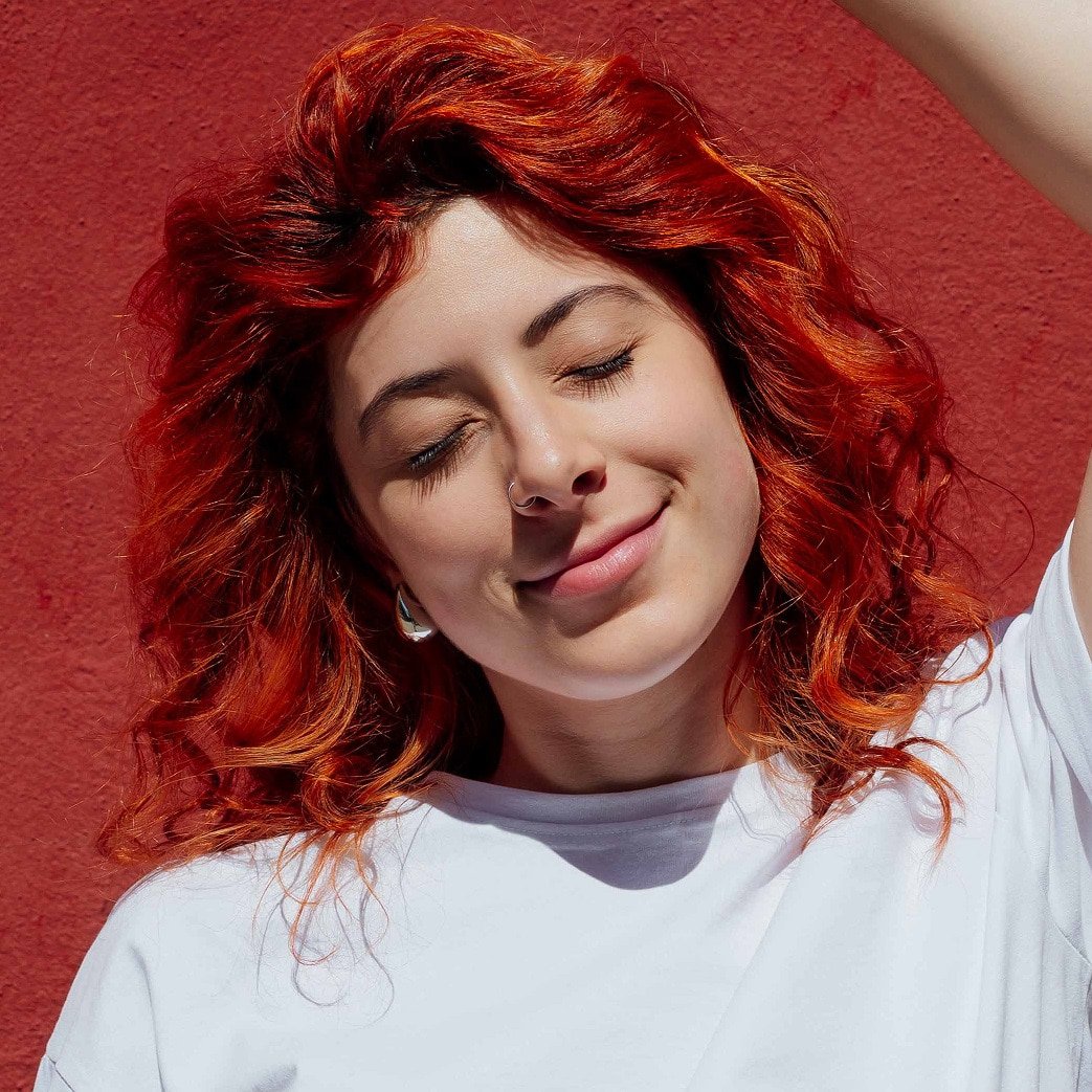 A woman enjoying her healthy, vibrant dyed red hair.